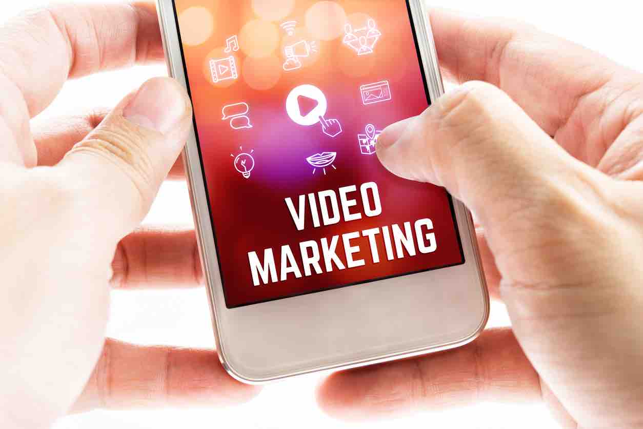 Close up Two hand holding mobile phone with Video marketing word and icons, Online Digital Marketing concept