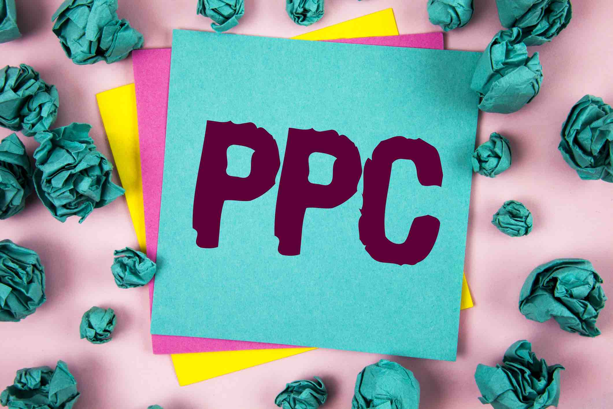 Handwriting text Ppc. Concept meaning Pay Per Click Advertising Strategies Direct Traffic to Websites written on Sticky Note Paper on plain background Crumpled Paper Balls next to it.