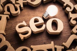 Seo abbreviation in scattered wood letters with glowing white light bulb